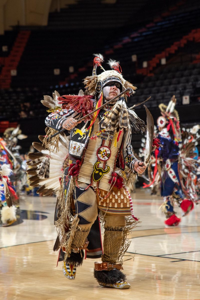 Men in indigenous clothing dance.