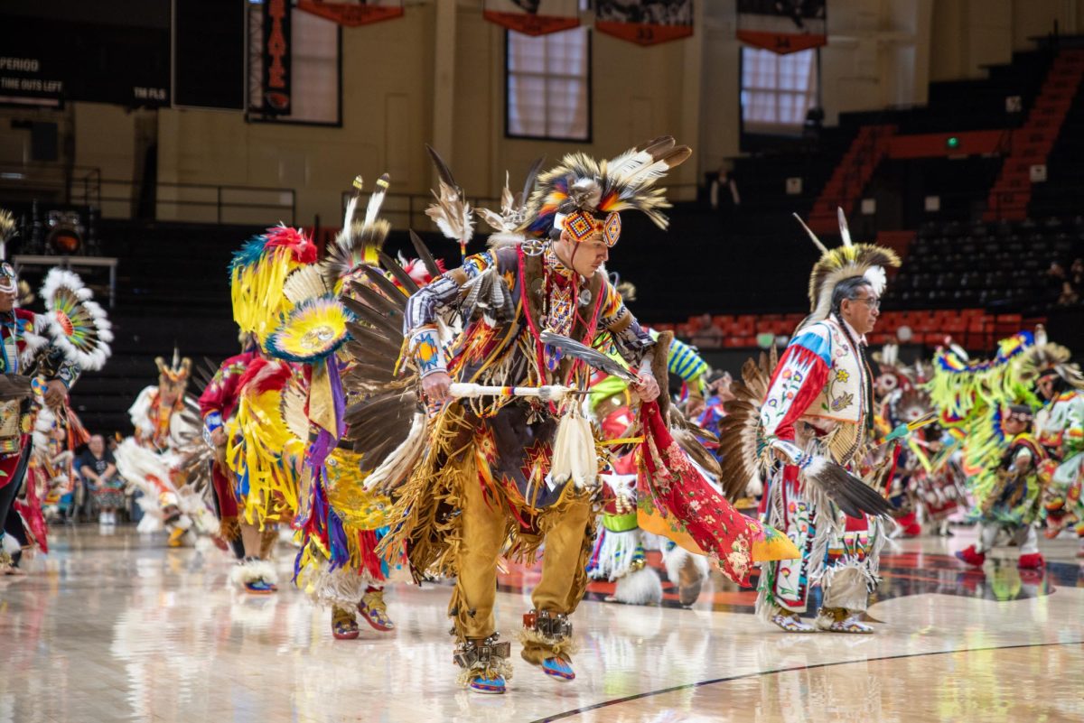 Men in indigenous clothing dance.