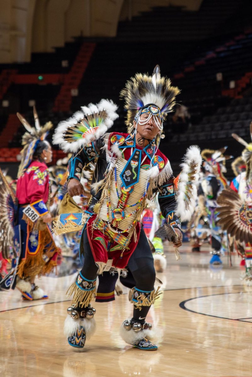 Men in indigenous clothing dance.