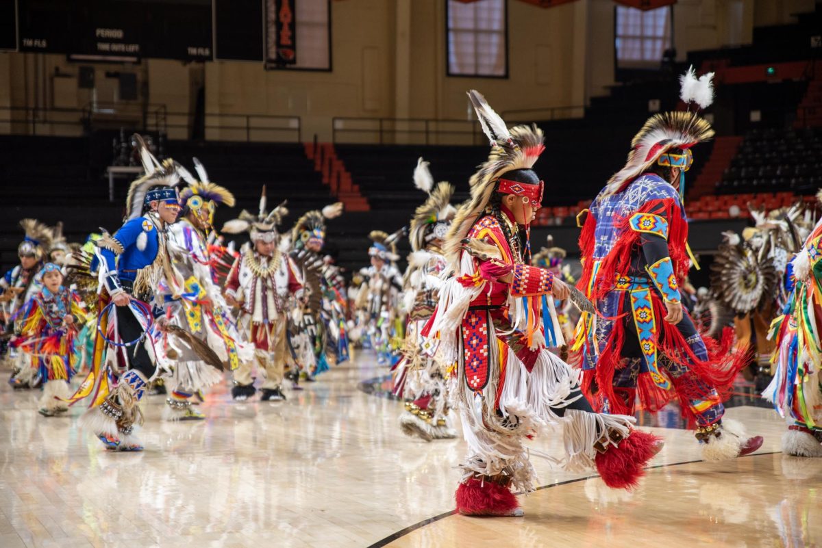 Men in indigenous clothing dance.