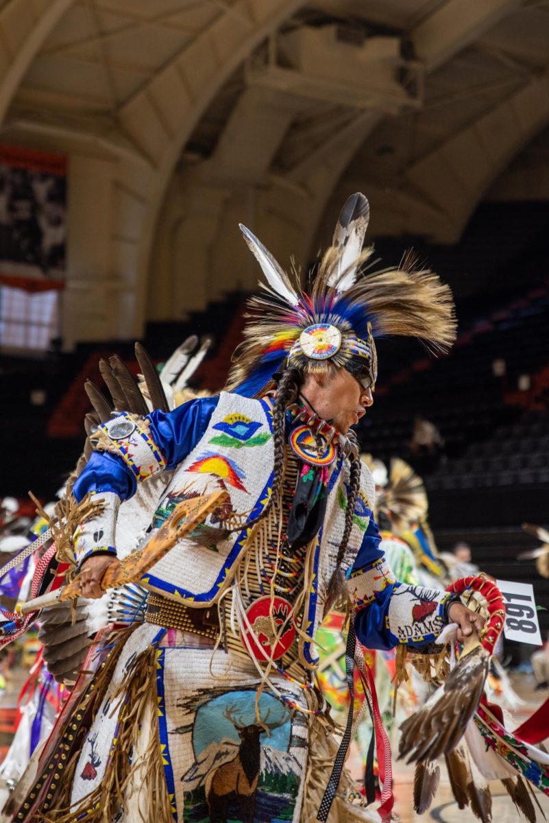 Men in indigenous clothing dance.