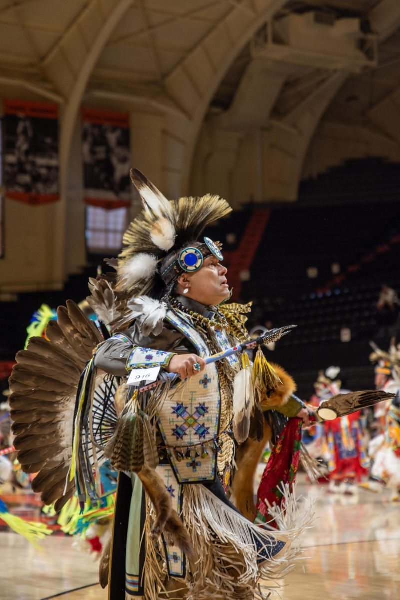 Men in indigenous clothing dance.