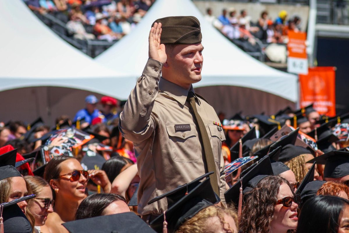 An ROTC member stands with his right hand up.
