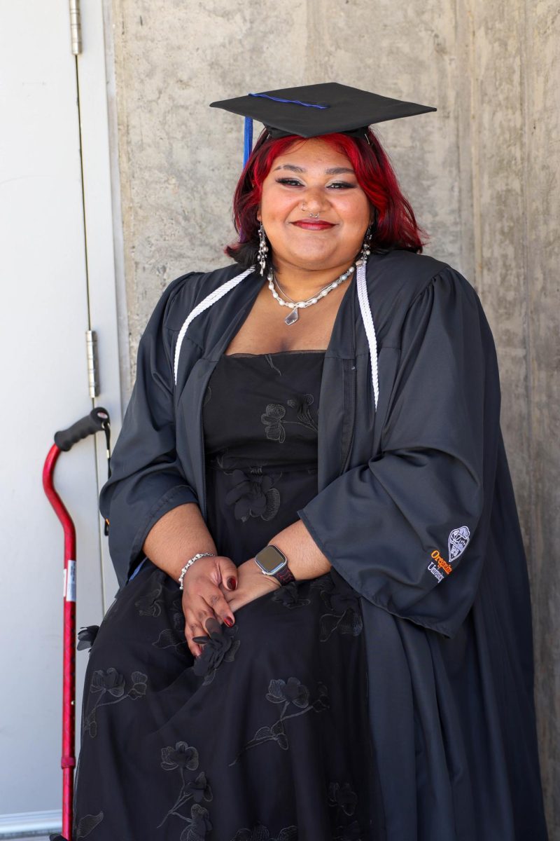 A graduate sits and smiles.