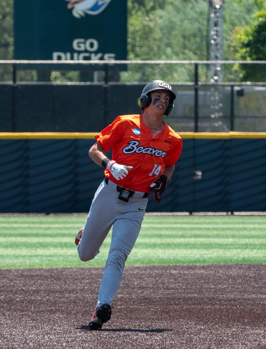 A baseball player runs on the field to third base.