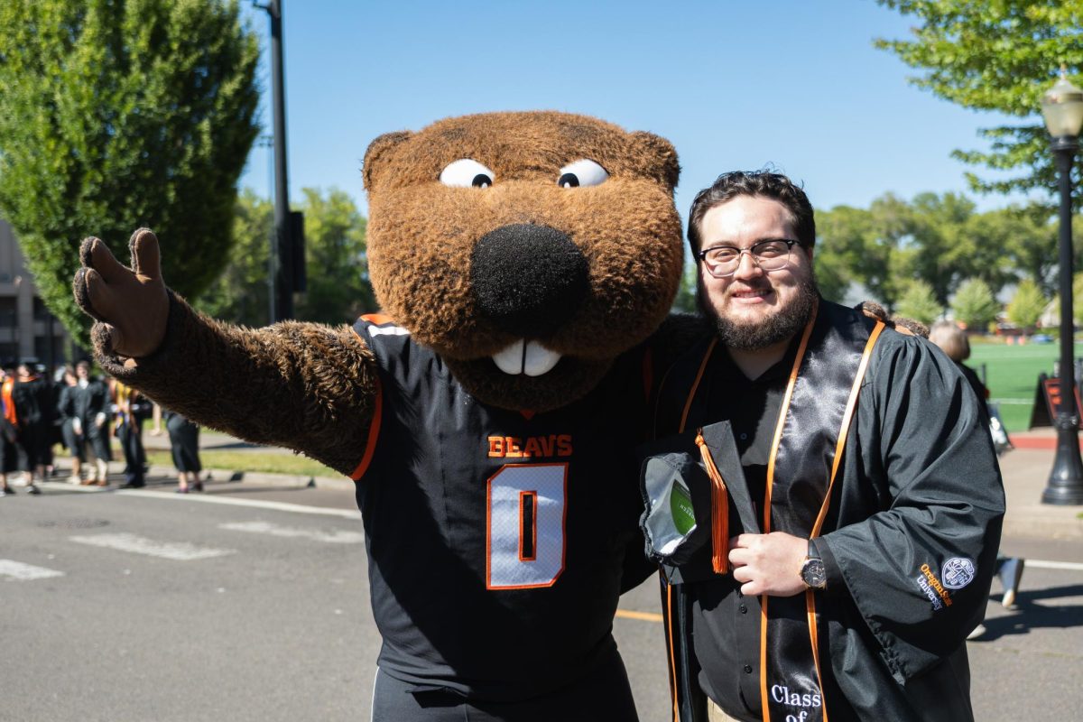 The OSU mascot poses with a graduate with a side hug.