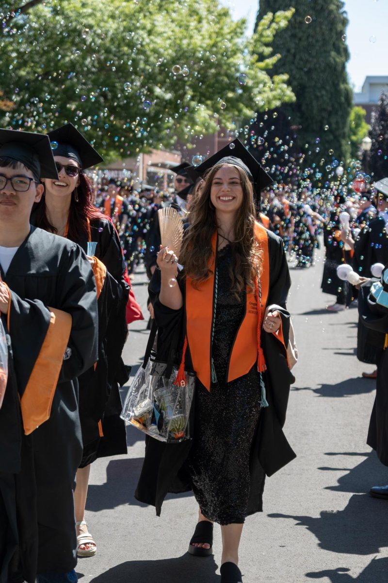 Graduates walk down a street.