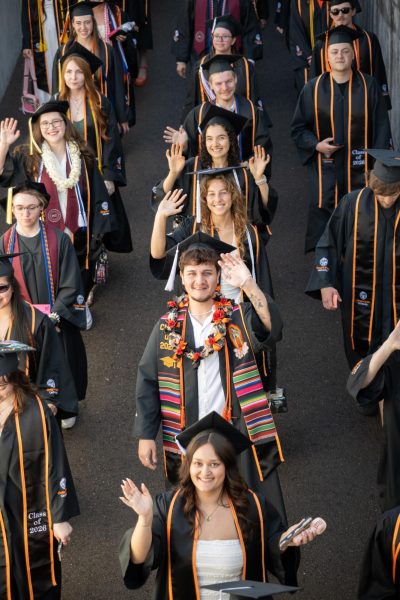 Graduates walk into the stadium and wave.