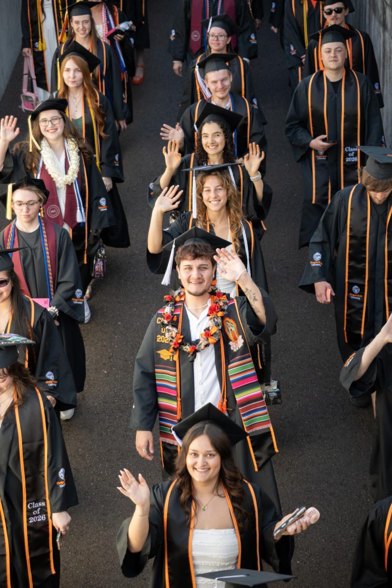 Graduates walk into the stadium and wave.