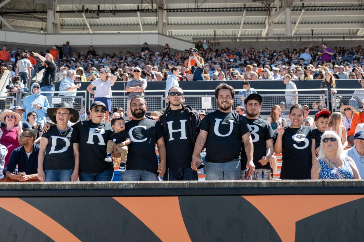 People stand in a line with shirts that each have a letter on it.