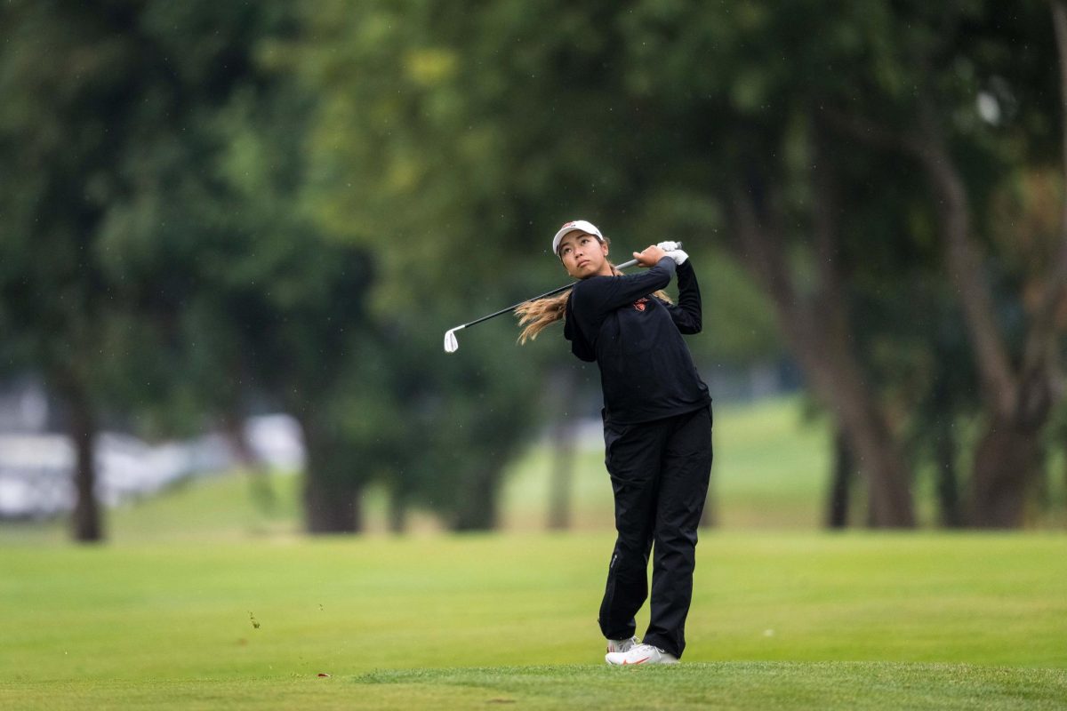 A woman swings a golf club.