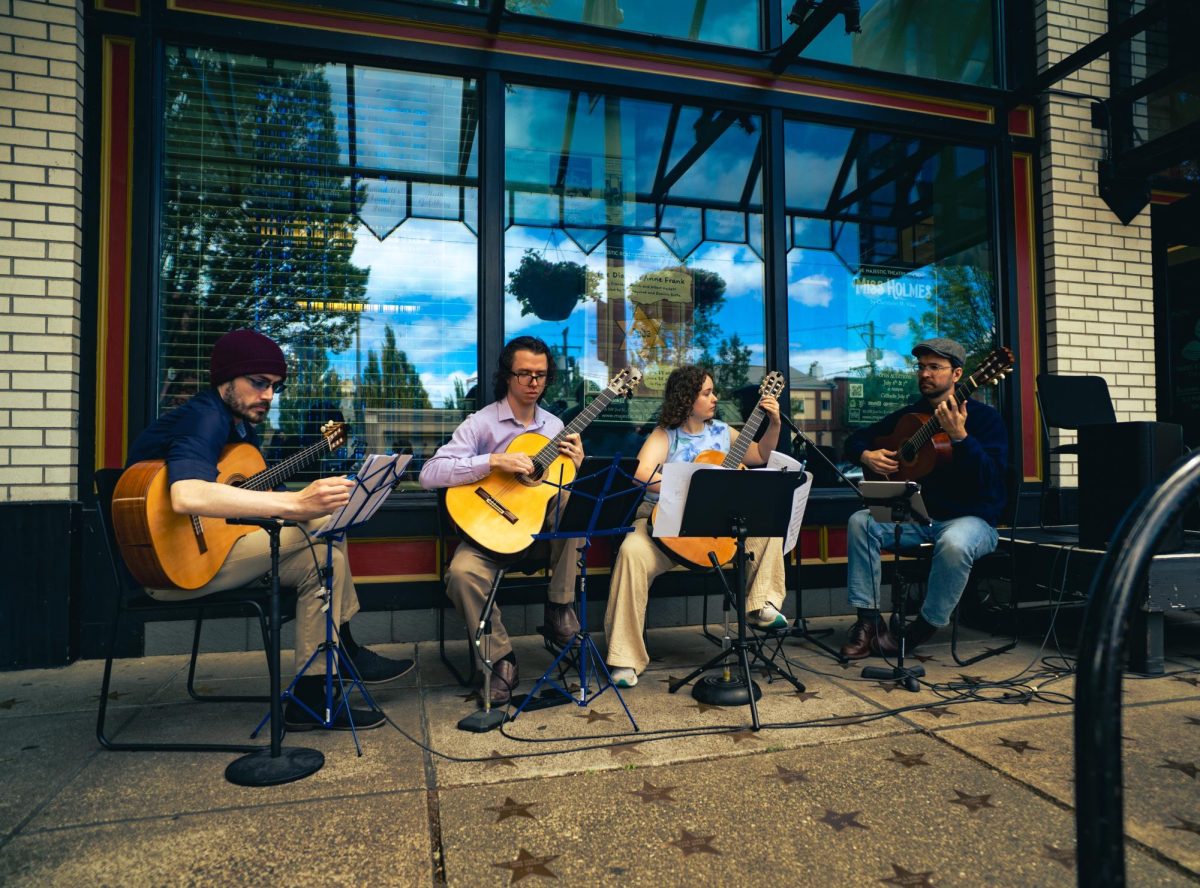 A group of four plays guitars