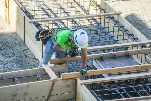 A construction worker uses a hammer at a worksite.