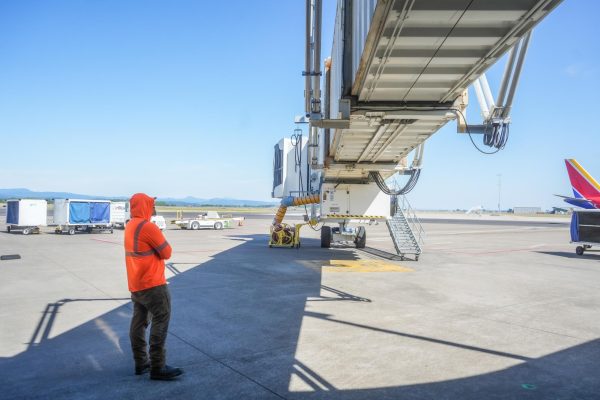 A man monitors a jet bridge on a tarmac.