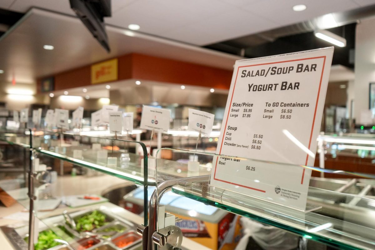 A price list for soups and salads sits on top of a sneeze guard.