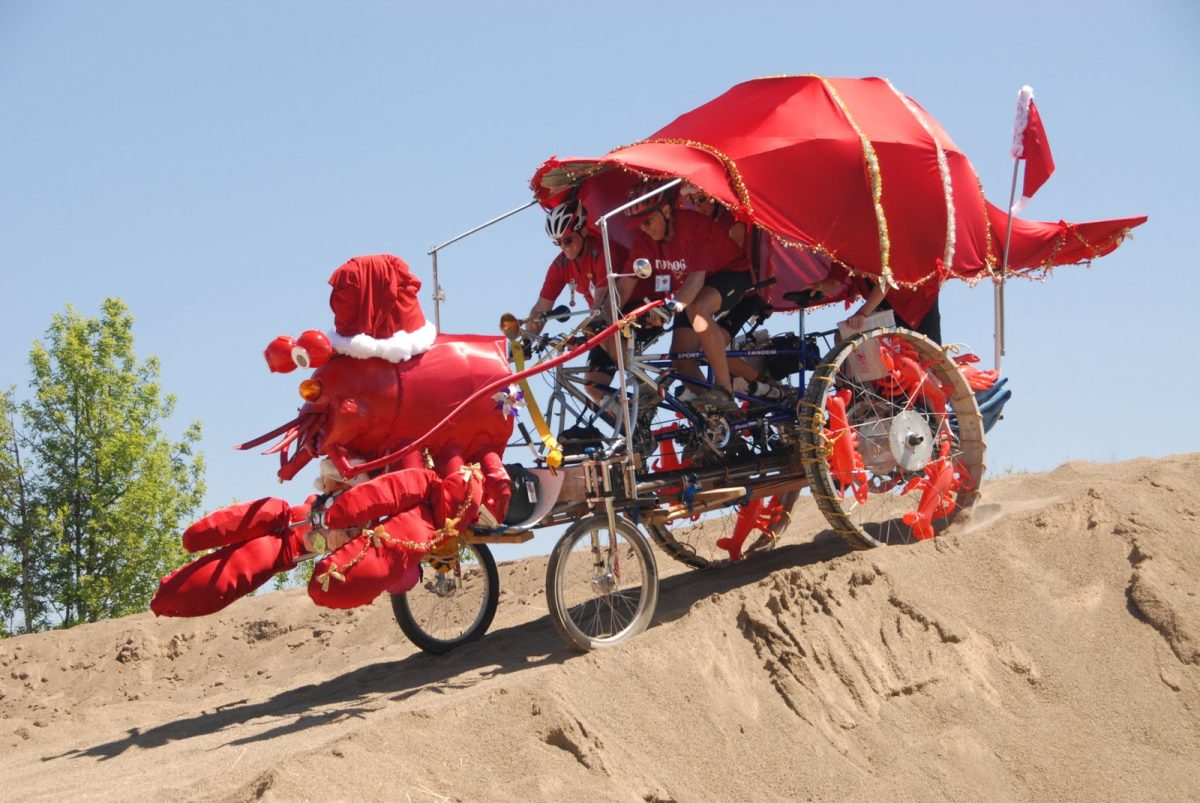 A group rides down a sand dune in their handmade vehicle in July 2025. The Graand Kinetic Challenge is an annual, two-day festival and race held in Corvallis, featuring pedal-pushed sculptures.