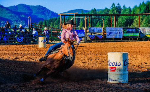 Cowgirl rides horse around an obstacle.